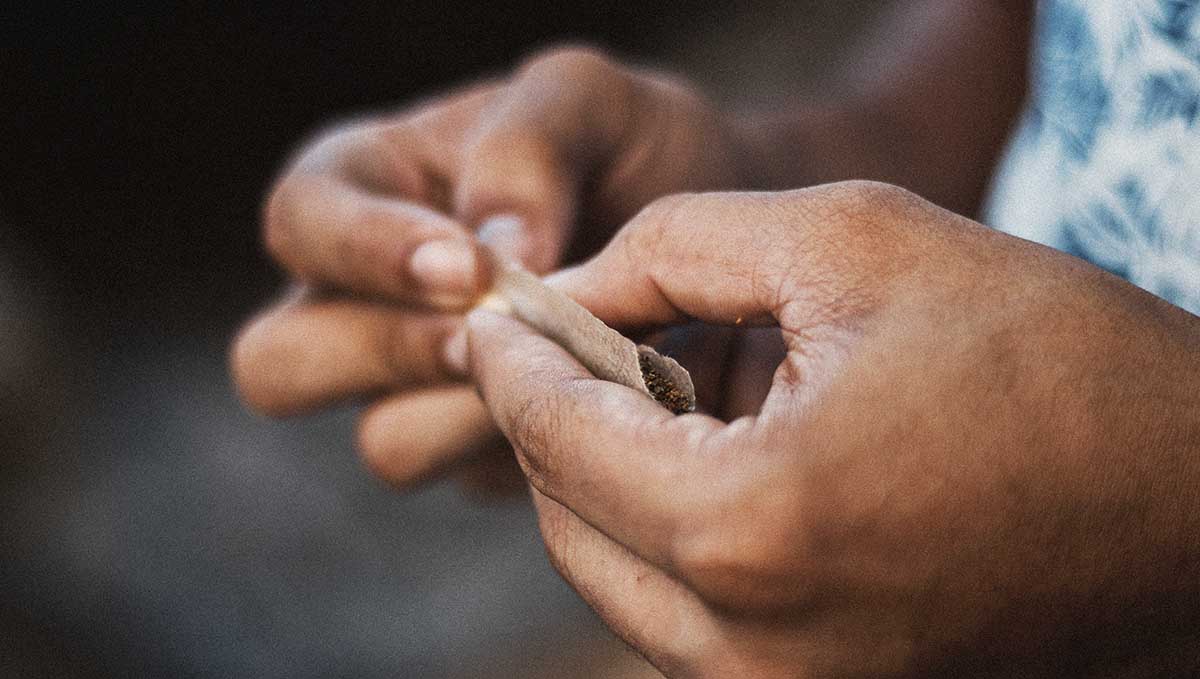 Spliff Definition - What Is a Spliff? A closeup of a person's hands as he rolls a cannabis cigarette