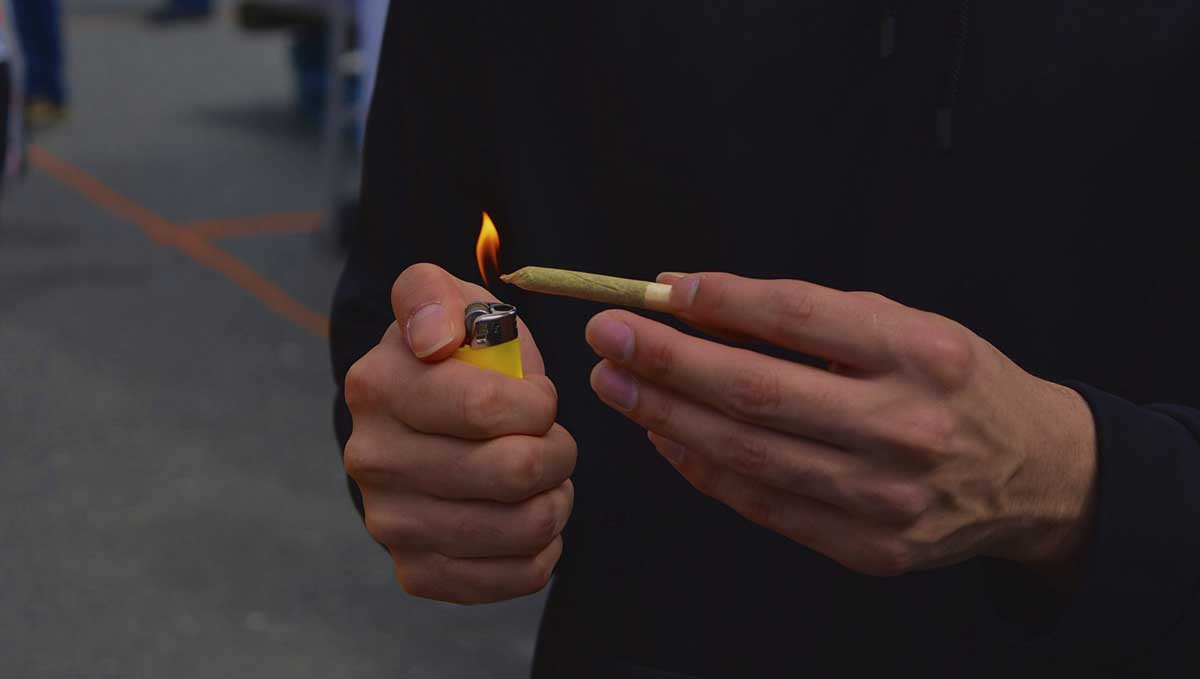 Spliff Definition &ndash; What Is a Spliff? A closeup of a man's hands as he lights up a pre-roll