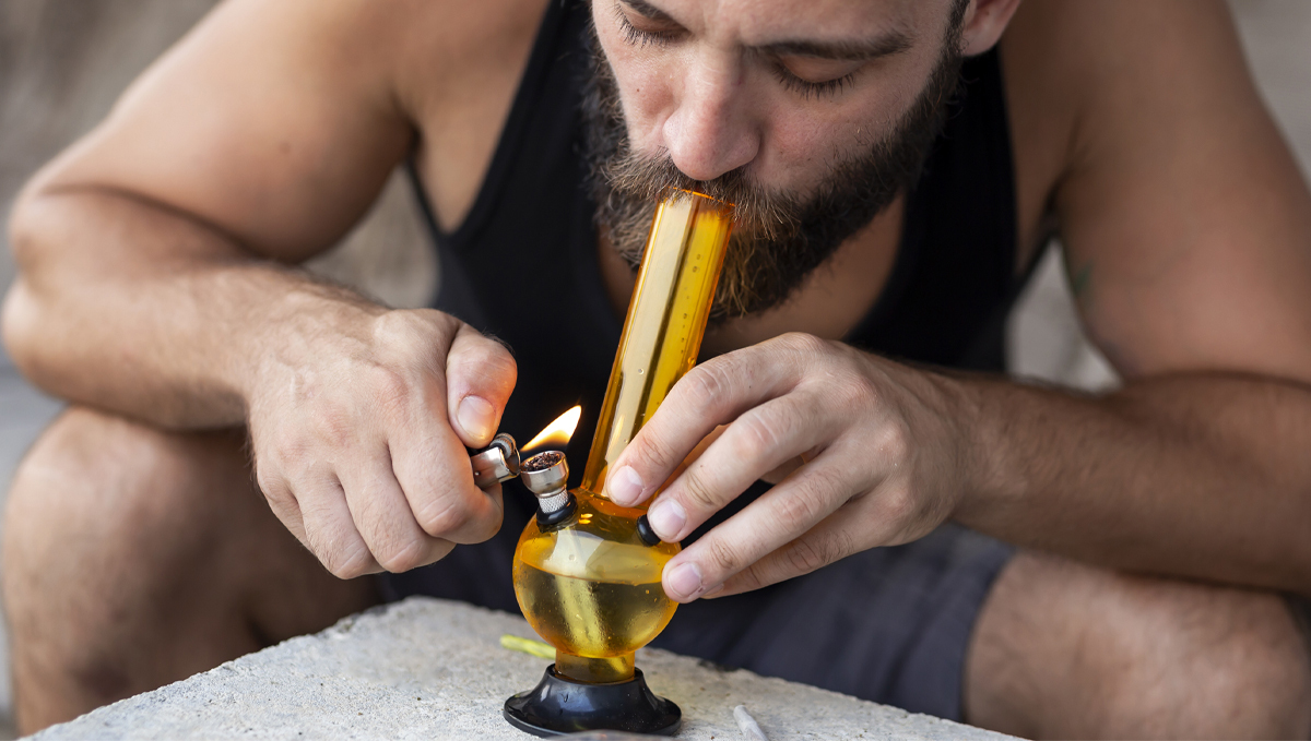PGR Weed &ndash; What Is Plant Growth Regulators and How to Spot it: A bearded young man smoking from a water bong