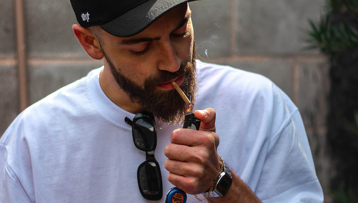 A young man lighting up a plants joint