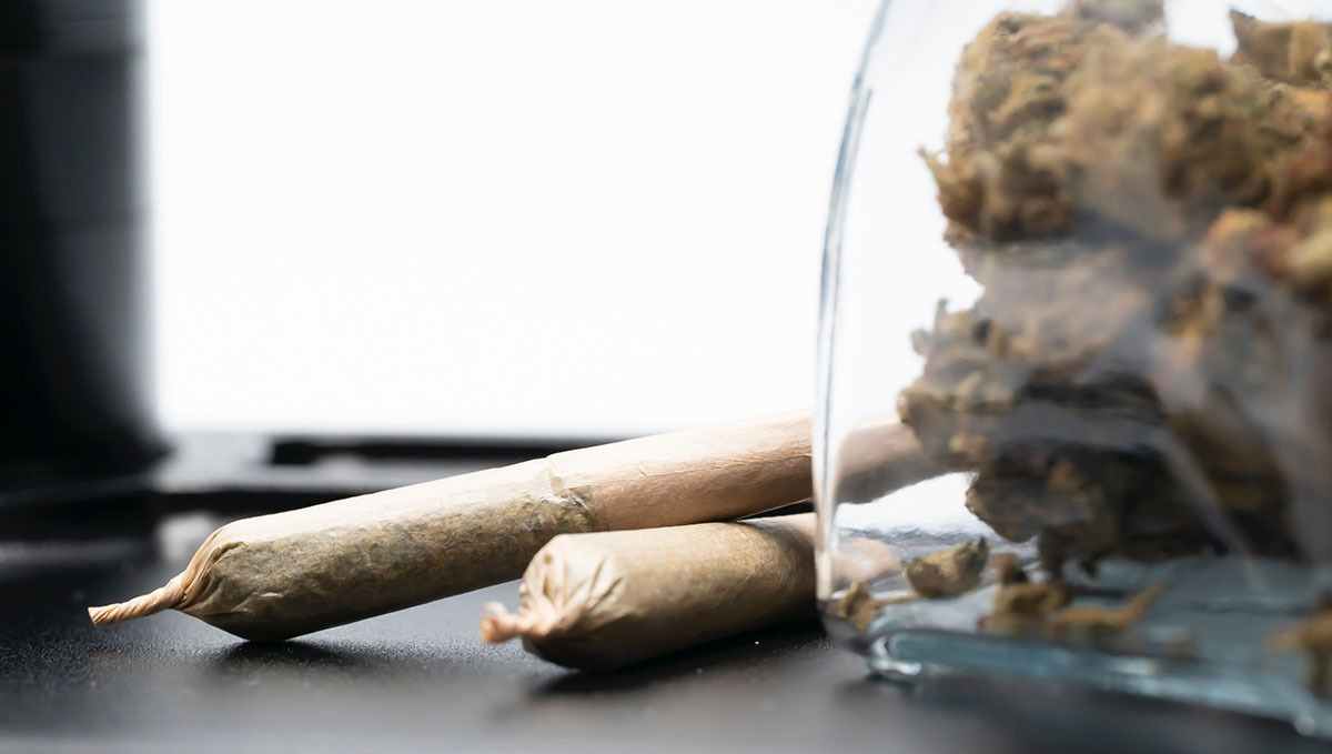 Thailand hebt das Verbot von Plants auf und eröffnet den legalen Handel: Ein Glas mit Plantsblüten und zwei danebenliegende Pre-Rolls