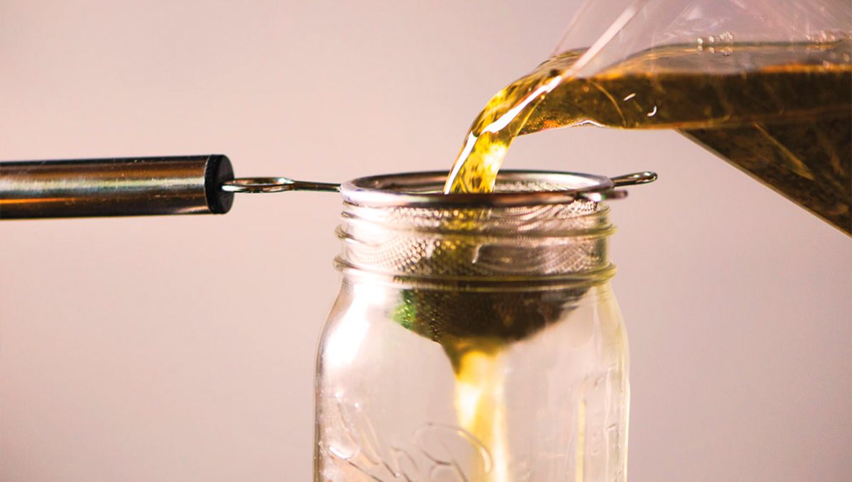 THC Syrup Explained: What Is THC Lean & How to Make It: Cannabis-infused oil filtered through a metal strainer